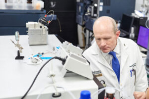 Neurologist Randall J. Bateman, MD, the Charles F. and Joanne Knight Distinguished Professor of Neurology, inspects a mass spectrometry machine at Washington University School of Medicine in St. Louis. Using mass spectrometry, Bateman and colleagues have developed a blood test that is up to 93% accurate at identifying people at risk of Alzheimer's dementia. (Photo: Matt Miller/School of Medicine)