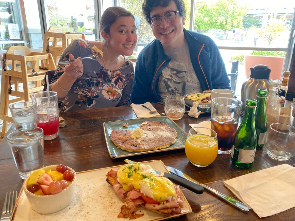 Man and woman at a table laden with delicious breakfast food