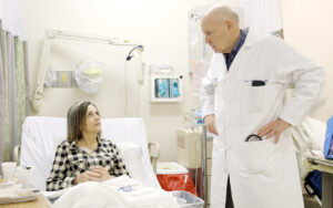 John P. Atkinson, MD, (right) talks with patient Kim Morey, of Bentonville, Ark., a participant in the first clinical trial evaluating a potential drug therapy for a rare, fatal disease called retinal vasculopathy with cerebral leukodystrophy (RVCL). Atkinson, who directs the RVCL Research Center at Washington University School of Medicine in St. Louis, is leading the trial and has played a key role in research to describe the disease and develop a genetic test to identify it.