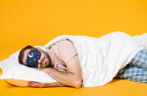 Man lying down with blanket and sleep mask
