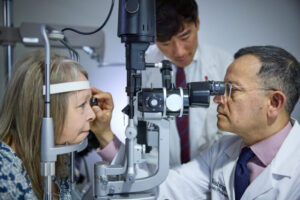 Ophthalmologist Rajendra S. Apte, MD, PhD, (right), of Washington University School of Medicine in St. Louis, examines patient Patricia Collins (left) while medical student Wilson Wang observes. Collins is a participant in a clinical trial that tests the safety and efficacy of an FDA-approved drug in stabilizing vision in patients with RVCL-S, a rare genetic disease that affects tiny blood vessels in the body.