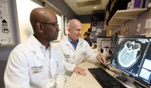 Opeolu Adeoye, MD, and Peter Panagos, MD, (right) both professors of emergency medicine at Washington University School of Medicine in St. Louis, analyze a brain scan for stroke damage. Adeoye led a national clinical trial that found that two anti-coagulant medications are ineffective at improving post-treatment outcomes for stroke patients. (Photo: Tim Miller)